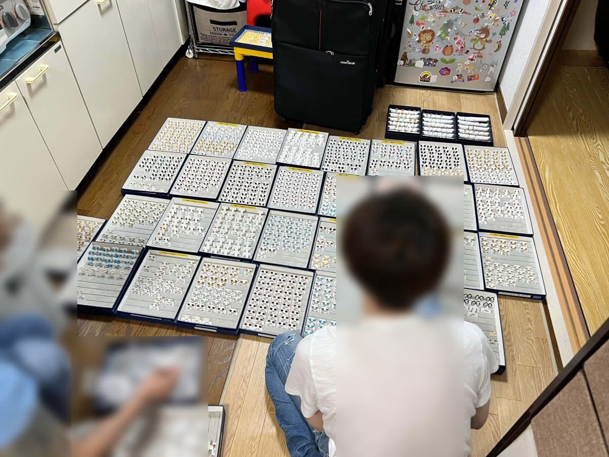 2021年、床に並べたピアスのトレイを仕分けする様子
